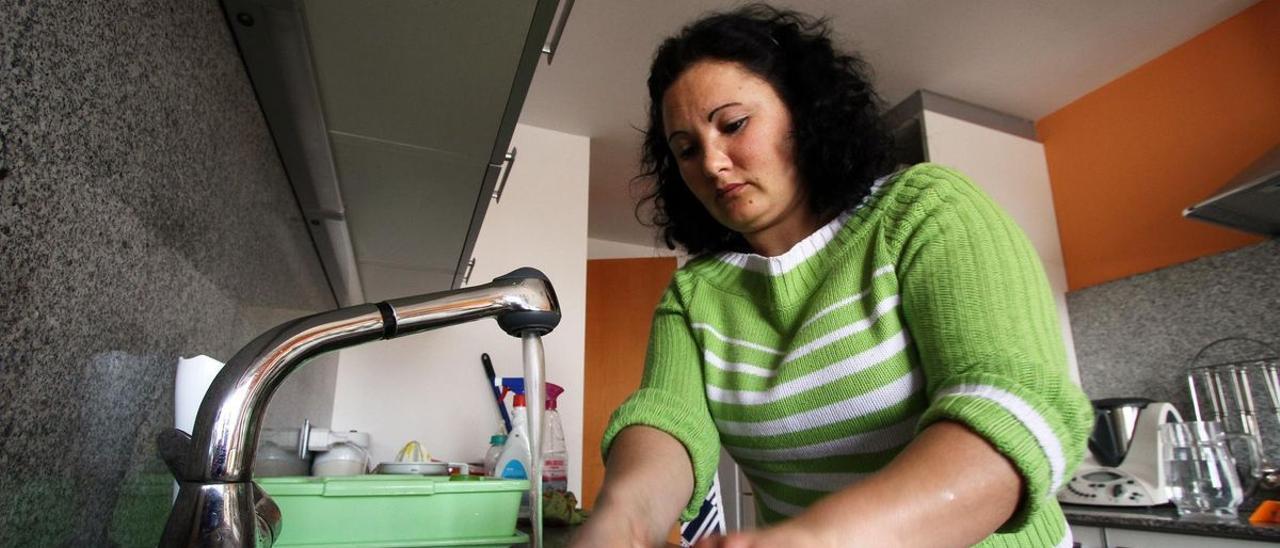 Una trabajadora del hogar friega los platos en un domicilio durante su jornada laboral.