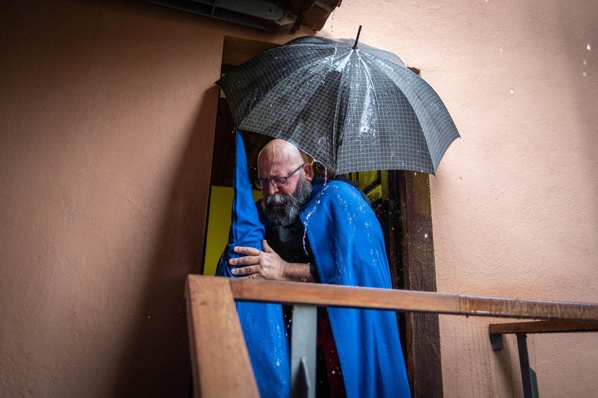 Un cofrade se resguarda de la lluvia.