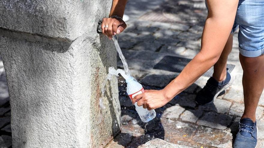 Un hombre rellena su botella con agua de una fuente para paliar las altas temperaturas.