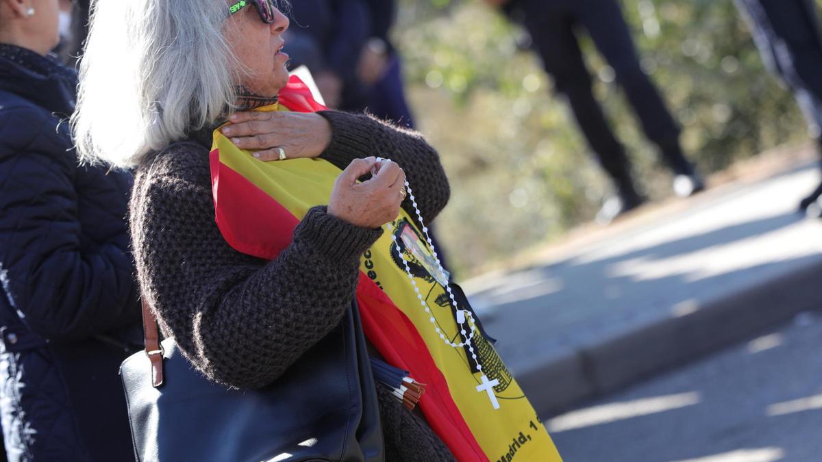 Archivo - Una nostálgica del franquismo con una bandera de la dictadura y un rosario espera la llegada del féretro con los restos de Francisco Franco al  cementerio de El Pardo-Mingorrubio, donde será inhumado, en El Pardo (Madrid, España), a 24 de octubr