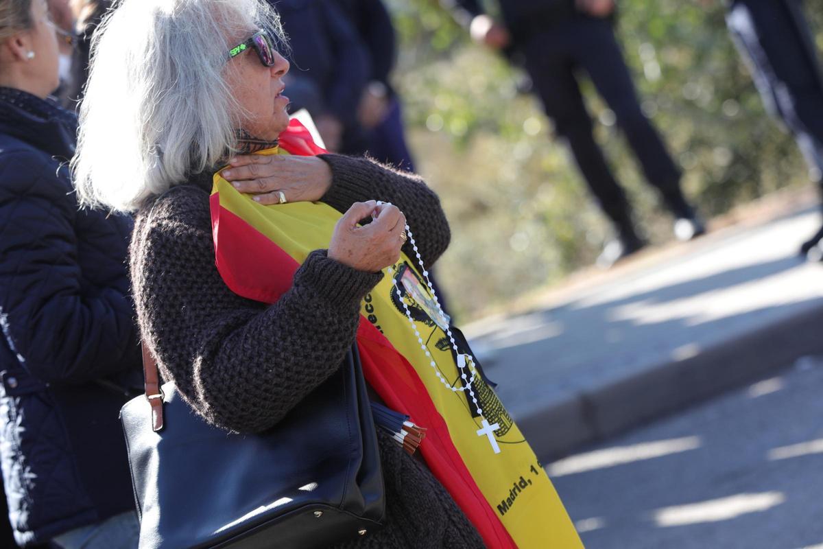 Archivo - Una nostálgica del franquismo con una bandera de la dictadura y un rosario espera la llegada del féretro con los restos de Francisco Franco al  cementerio de El Pardo-Mingorrubio, donde será inhumado, en El Pardo (Madrid, España), a 24 de octubr