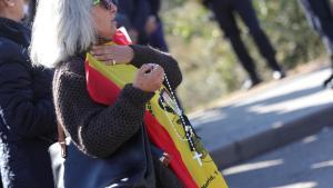 Archivo - Una nostálgica del franquismo con una bandera de la dictadura y un rosario espera la llegada del féretro con los restos de Francisco Franco al  cementerio de El Pardo-Mingorrubio, donde será inhumado, en El Pardo (Madrid, España), a 24 de octubr