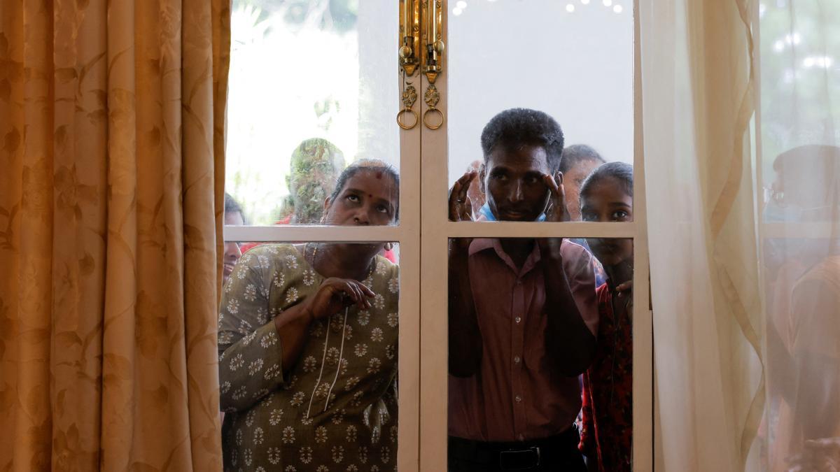 Un grupo de personas mira a través de una ventana durante una visita a la casa presidencial después de que los manifestantes entraran en el edificio.