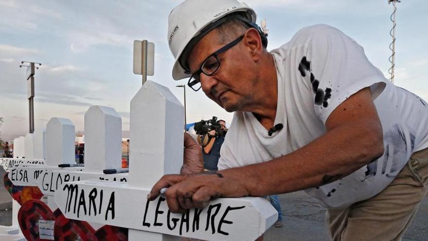 Un hombre coloca cruces en el lugar del tiroteo.