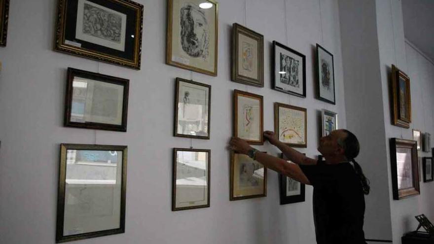El galerista Javier Lillo del Valle coloca algunos grabados en las paredes de la sala de subastas.