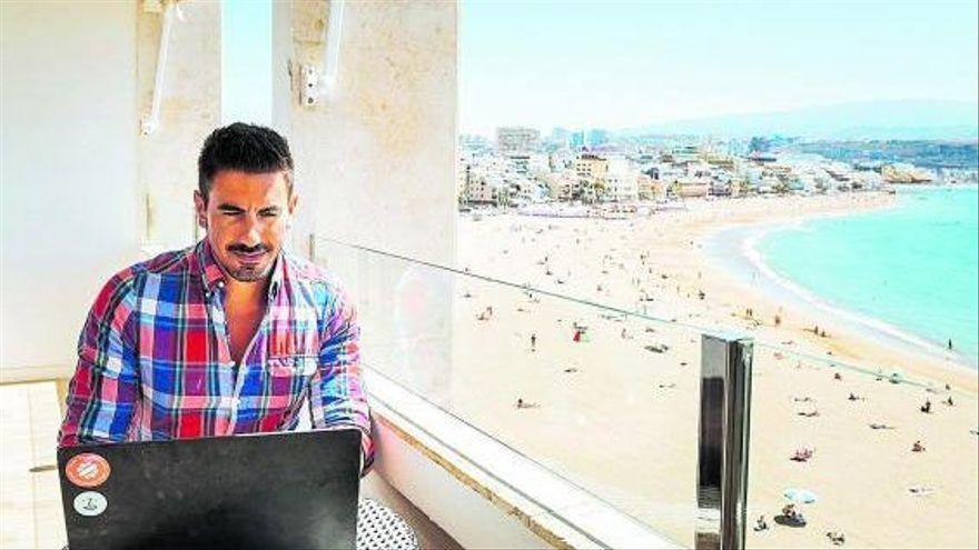 Un hombre trabaja con un ordenador en el balcón de un hotel.