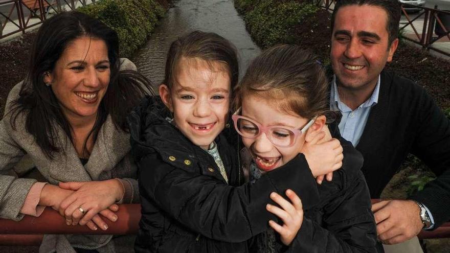 Martína y Antía se abrazan ante la cariñosa mirada de sus padres, Isabel Barrena y Jorge Mondelo, junto al río de O Con. // Iñaki Abella