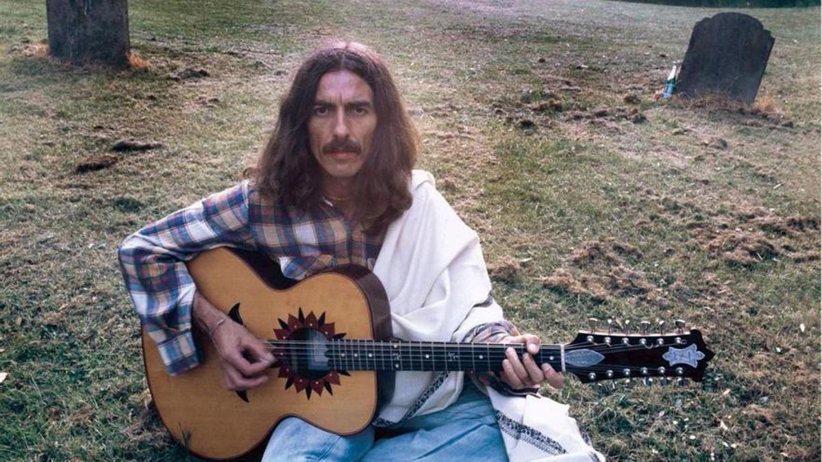 George Harrison en una imagen que lo resume: con el ceño fruncido, melena “hippie”, una guitarra acústica de doce cuerdas y rodeado de tumbas.