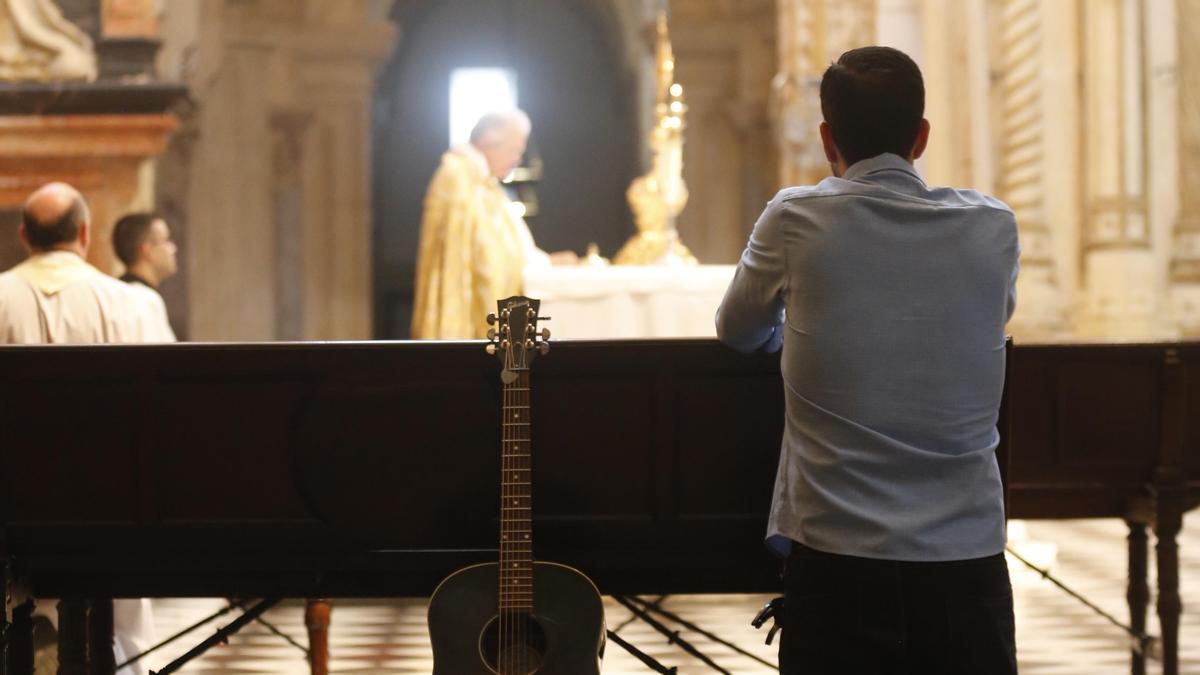 Un joven en la Catedral junto a su guitarra.
