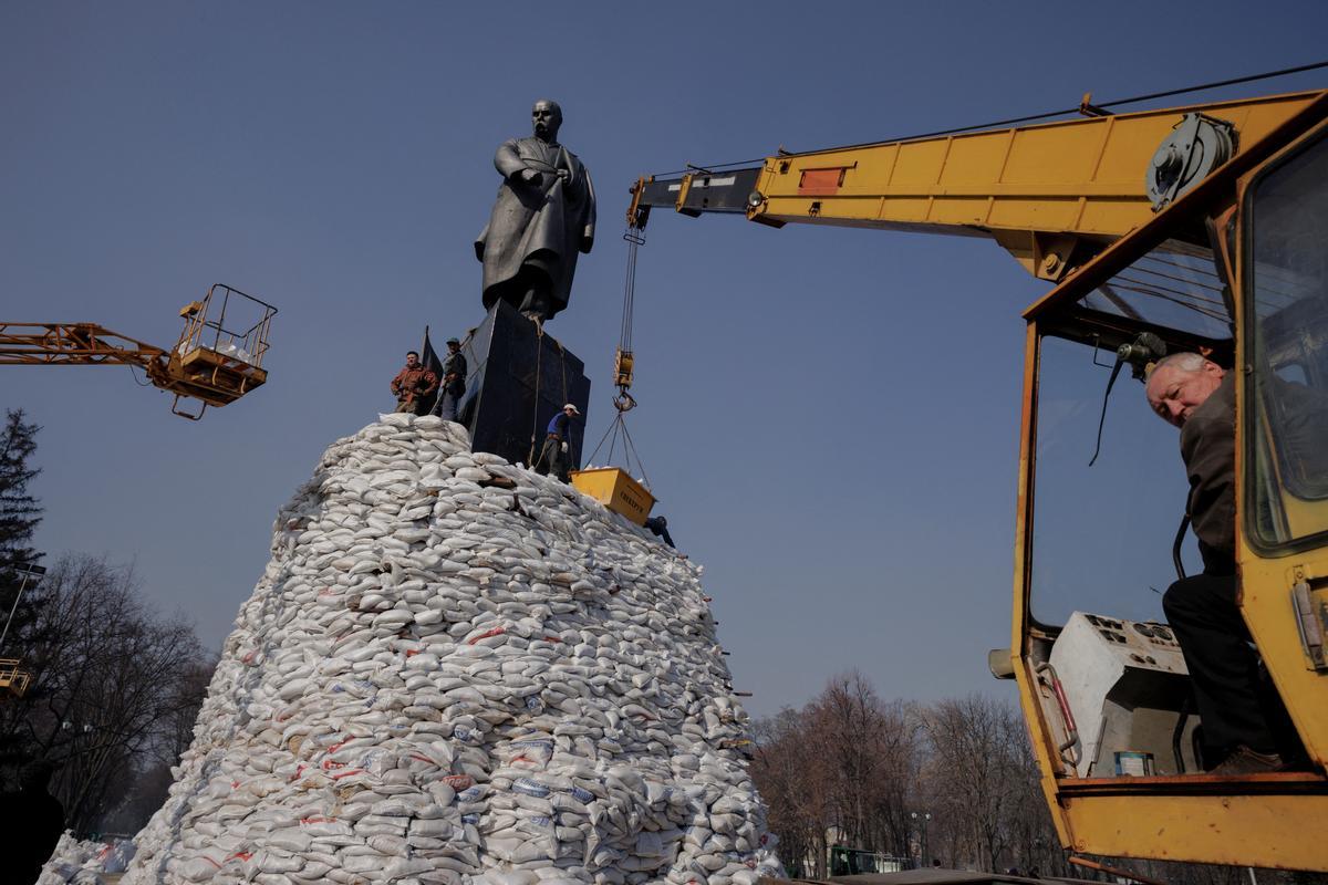 La gente apila bolsas de arena alrededor del monumento al poeta ucraniano Taras Shevchenko para protegerlo contra los daños causados por los bombardeos mientras continúa el ataque de Rusia contra Ucrania, en Kharkiv, Ucrania.