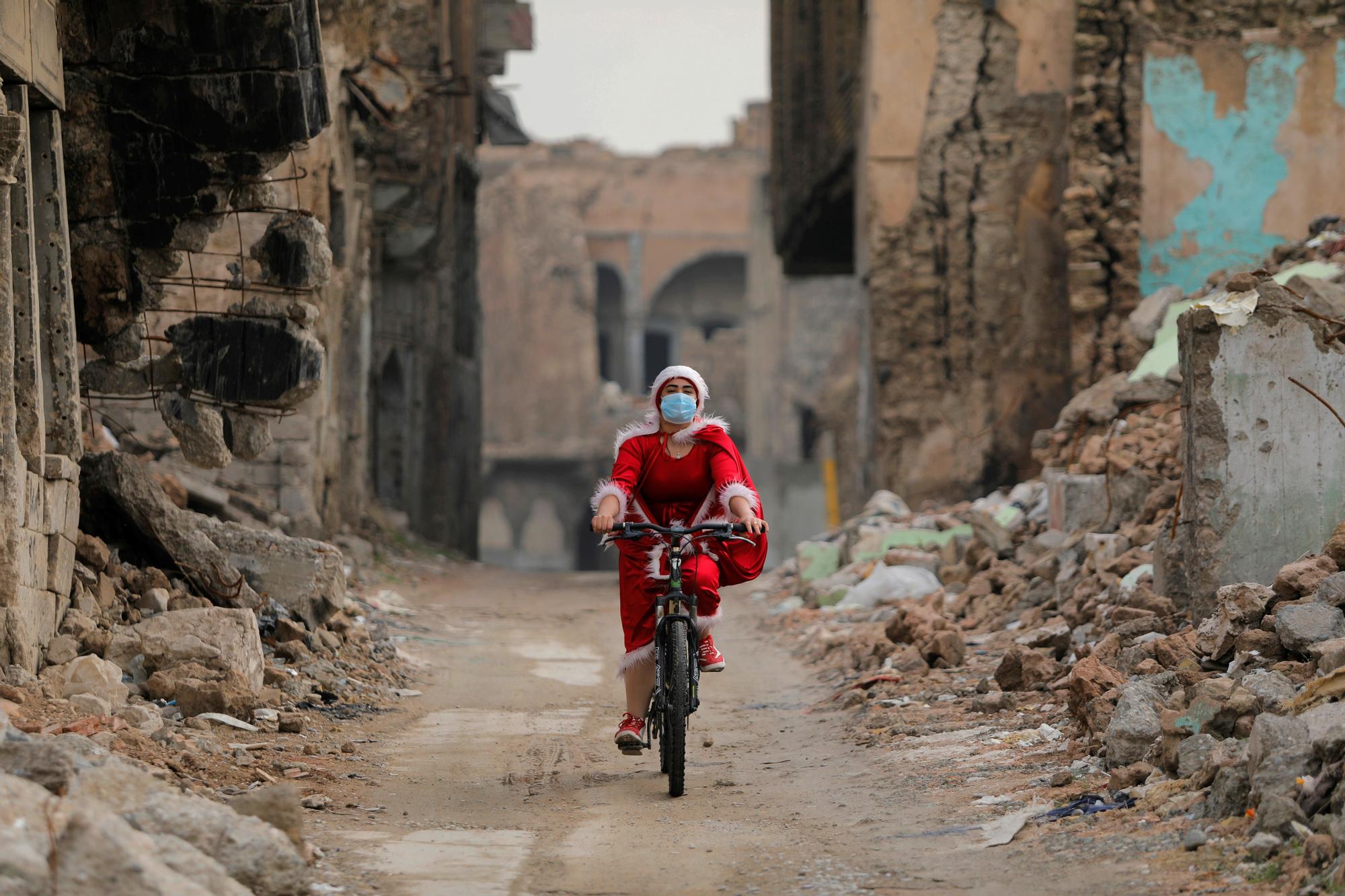 Una mujer iraquí pedalea vestida de Papa Noel entre las ruinas de la ciudad vieja de Mosul
