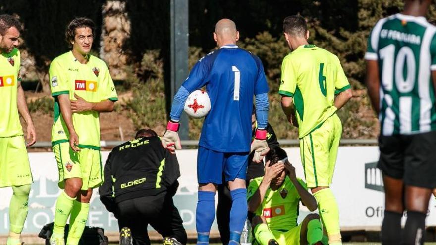 Los jugadores del Elche miran como atienden a Manu tras sufrir la brecha en la cabeza