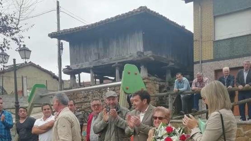 Elena Pérez Rivas, con un ramo de flores, durante el acto, junto al alcalde de Laviana, Julio García, en Canzana.