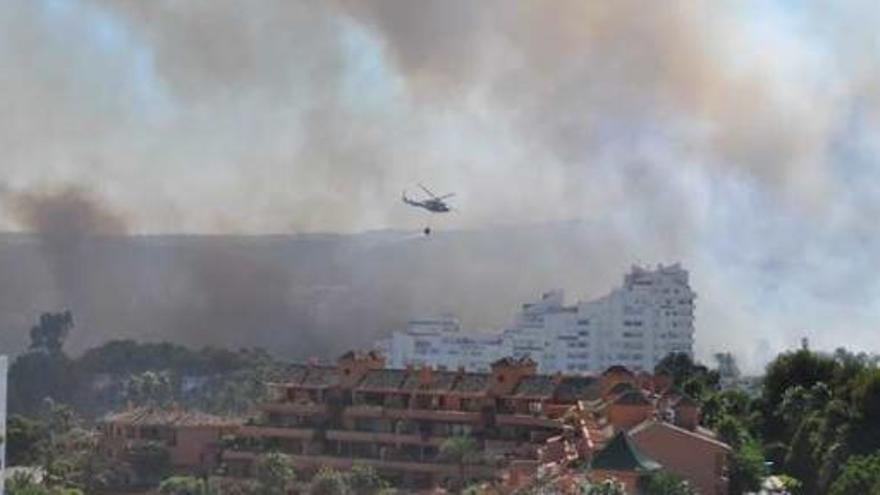 Un helicópetero sobrevuela una de las zonas urbanas afectadas por el incendio.