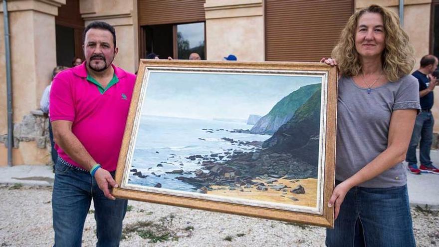 Ana Fernández y Miguel Ángel Somoano, directivos de la asociación, con el lienzo de Pepe Zapico.