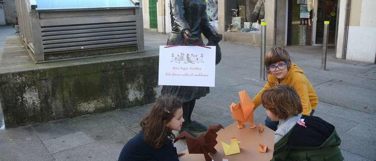 Los niños colocan las gallinas de cartón ante la escultura ubicada en la calle Sierra. // Rafa Vázquez