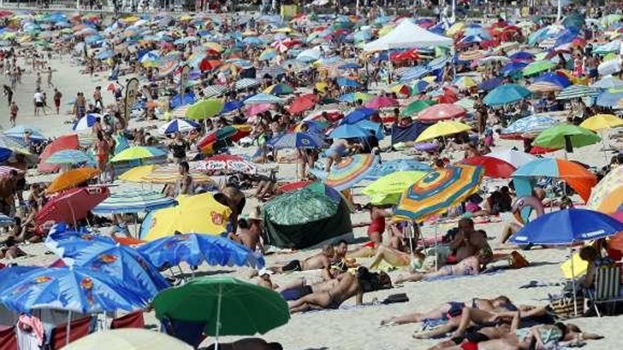 Multitud de bañistas con sombrillas, ayer, en la playa.