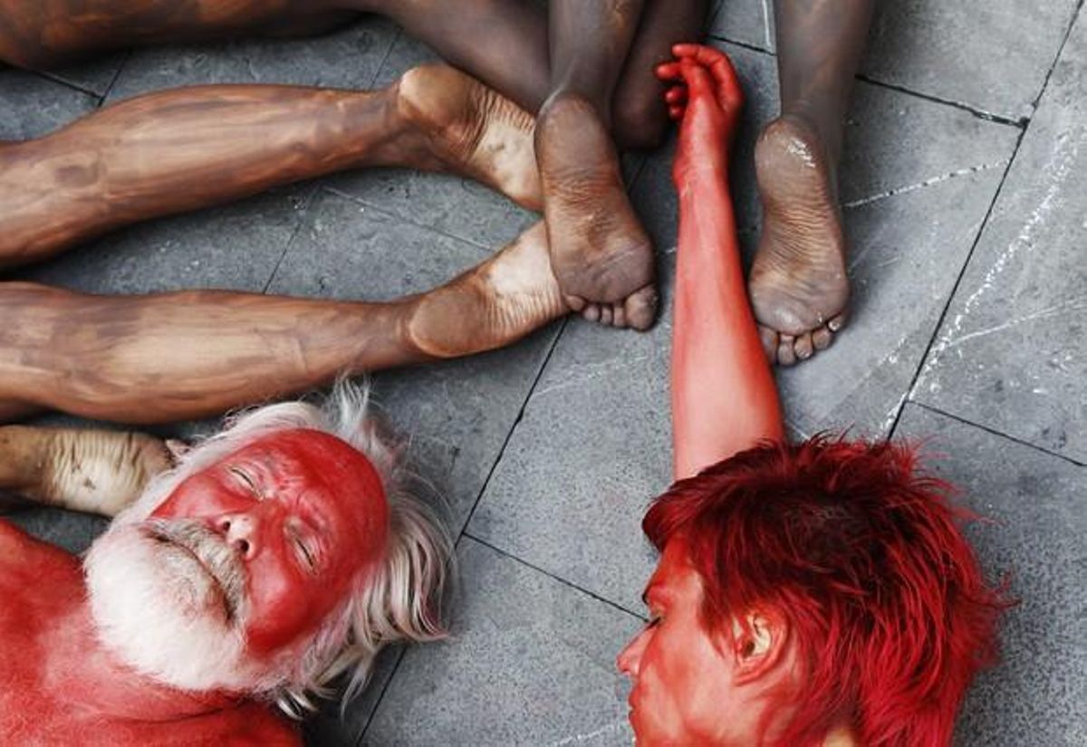 Animal {rights} {protesters} {lie} {covered} in {fake} blood and black {paint} as {they} {form} the {shape} of a bull {during} a {demonstration} in Pamplona