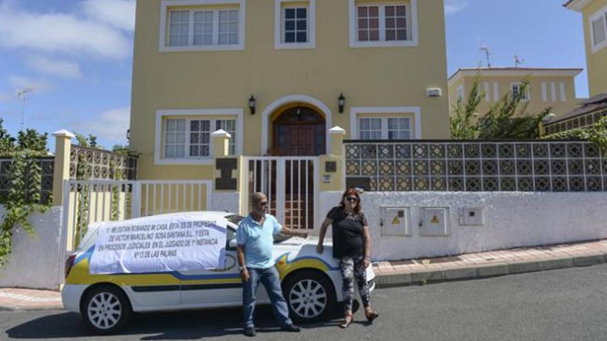 Víctor Sosa e Inma Lorenzo, junto al coche con una pancarta de protesta delante de su vivienda. | josé carlos guerra