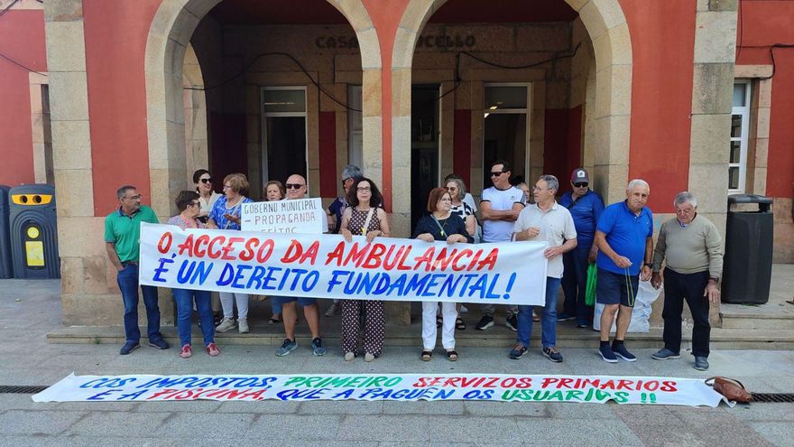 Vecinos de A Roza, a la entrada de la casa consistorial con pancartas.