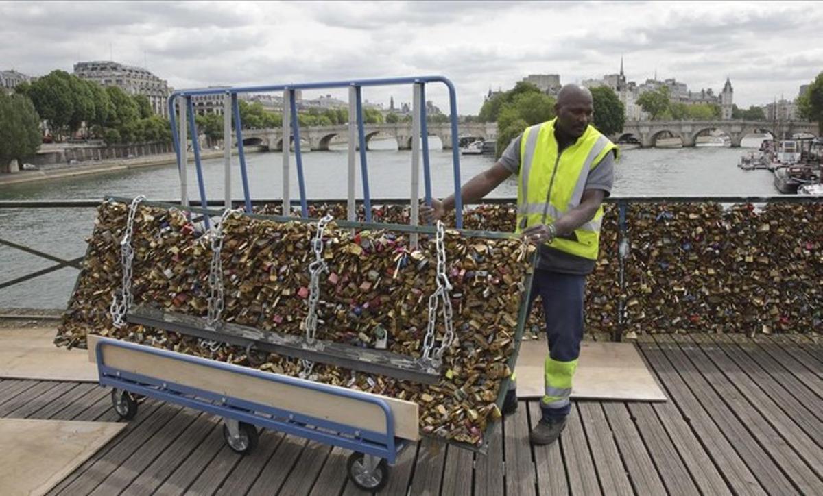 Un operari treballa en la retirada dels candaus de les baranes del pont de les Arts, a París.