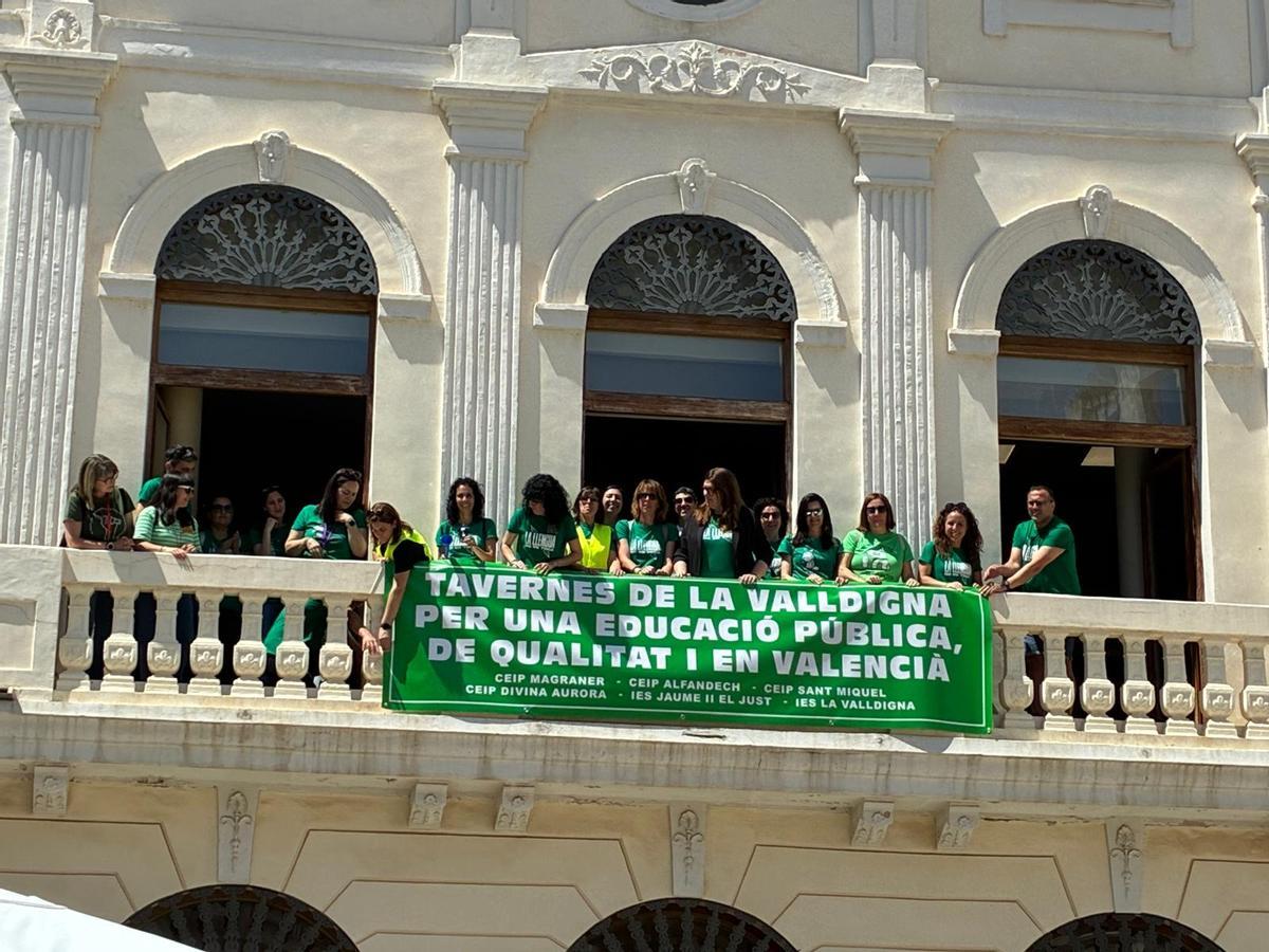 Docentes cuelgan la bandera en el balcón del ayuntamiento de Tavernes.