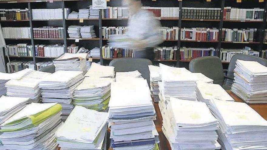 Un hombre frente a varias pilas de documentos en su puesto de trabajo. | Efe