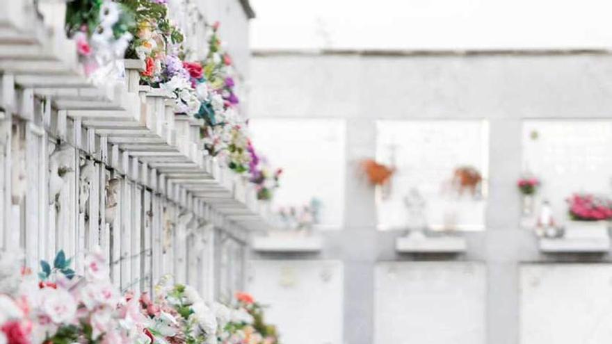 Una pareja, ayer, colocando unas flores en la zona de nichos del cementerio de La Carriona.