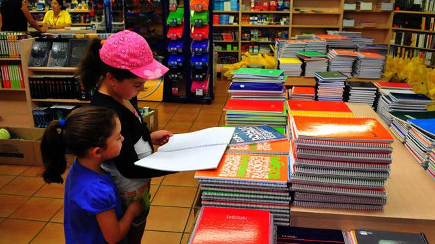 Dos niñas hojean libretas para el nuevo curso // I. Abella