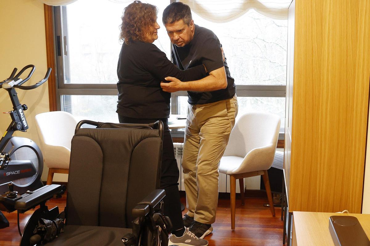 Estrella, mujer de Rafael Domínguez, enfermo de ELA, ayuda a su marido a levantarse. 13 diciembre 2023. Gustavo Santos