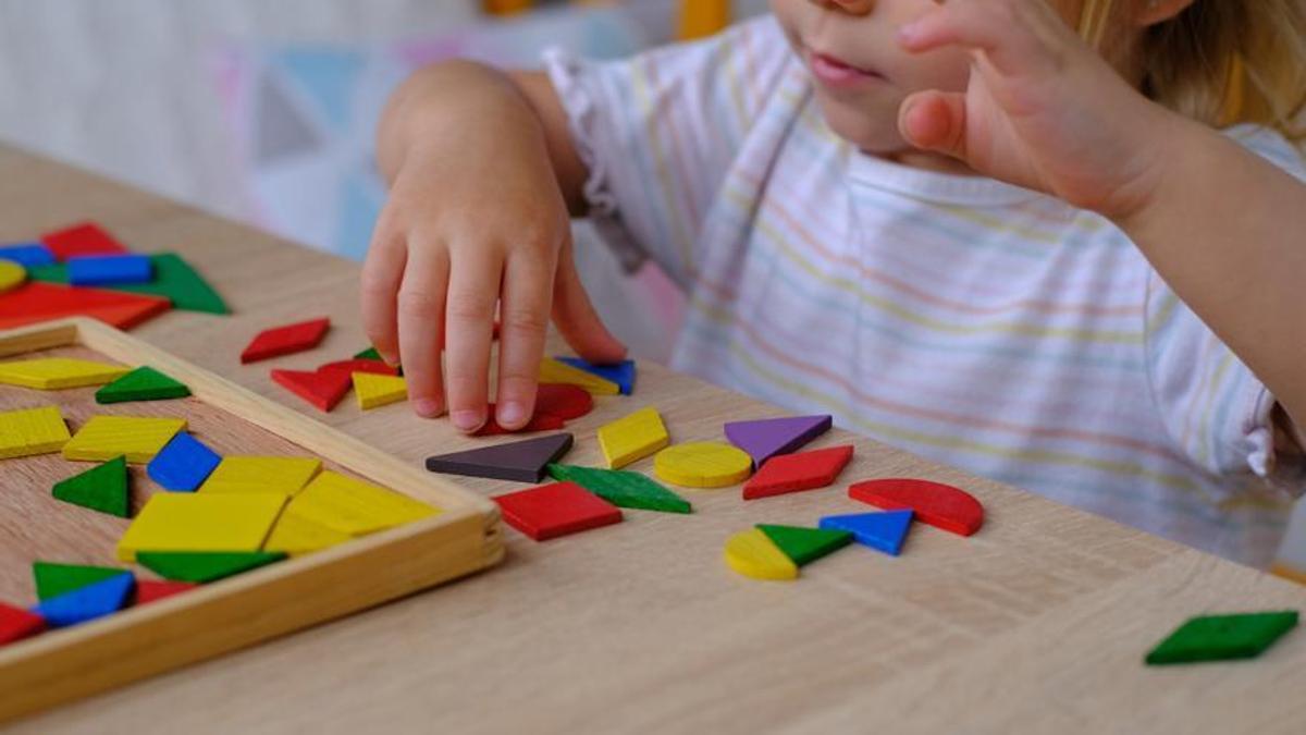 Un niño pequeño juega con piezas geométricas.