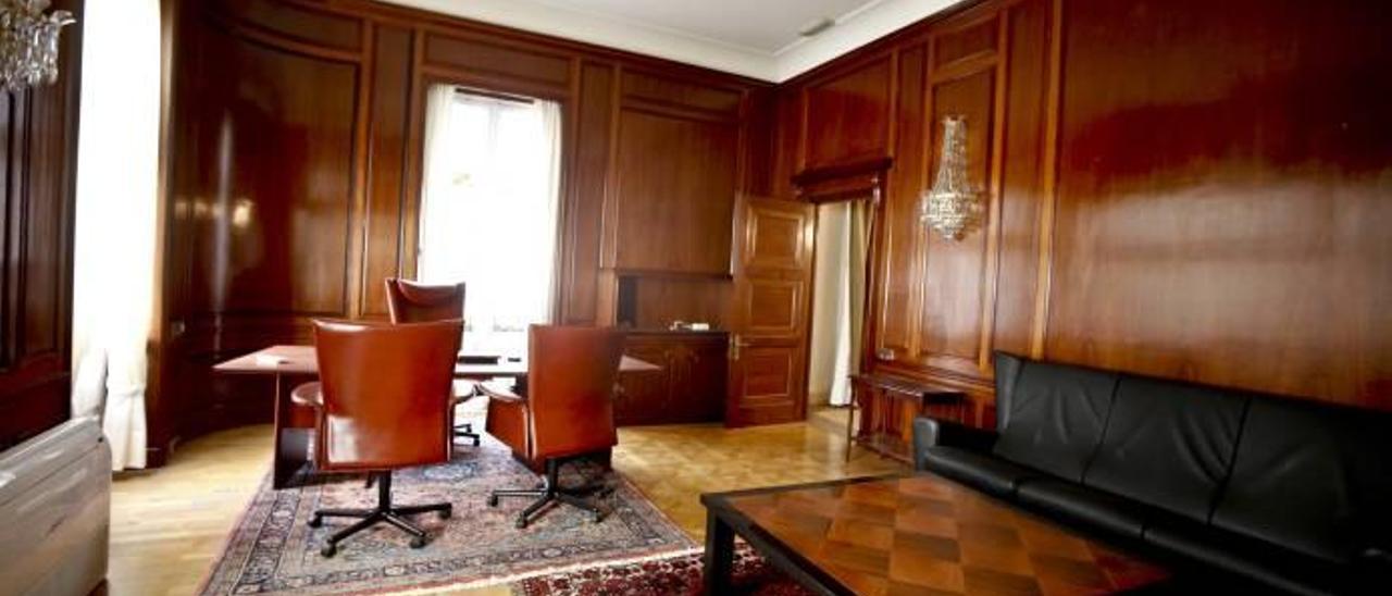 Un lujoso despacho, con las paredes recubiertas de madera, sillones de piel y alfombra clásica.