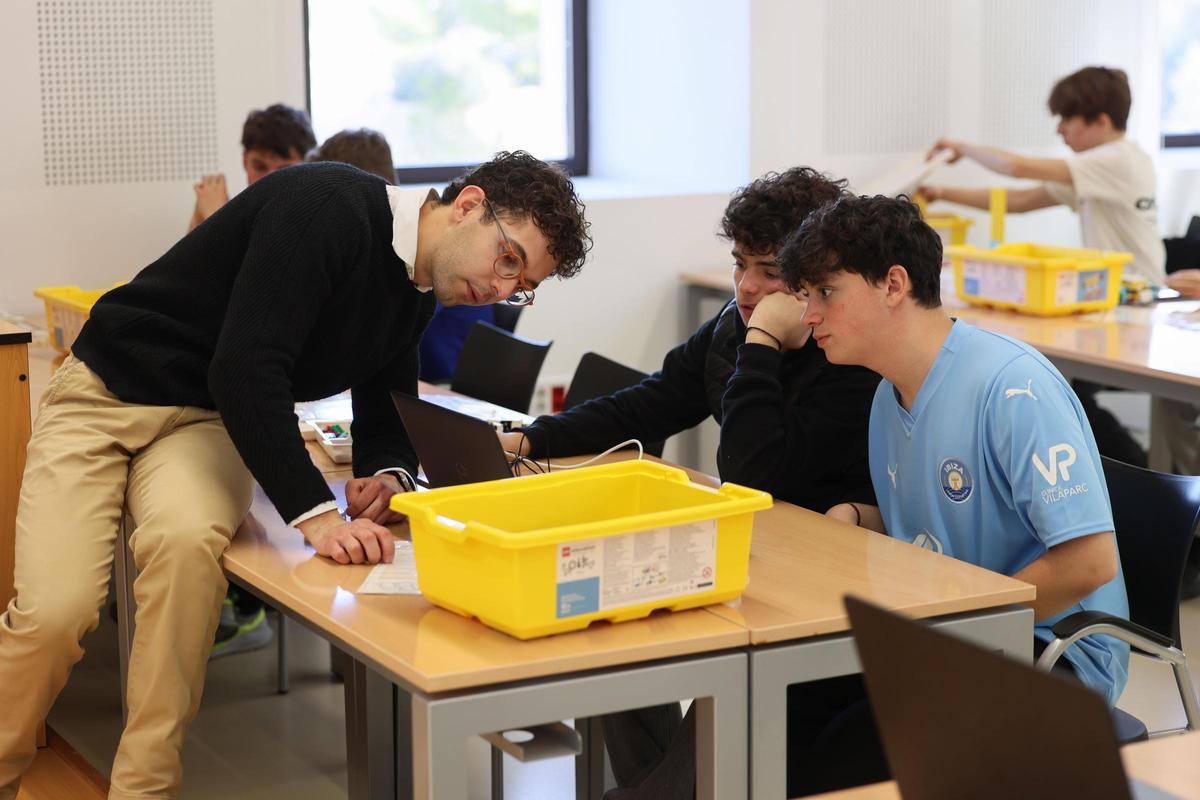 Uno de los encargados de la actividad de robótica, Lluc Cresoí, con dos de los alumnos.