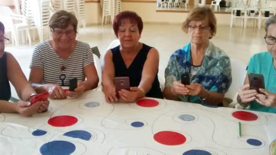 Un grup de dones manipula telèfons mòbils en el taller.