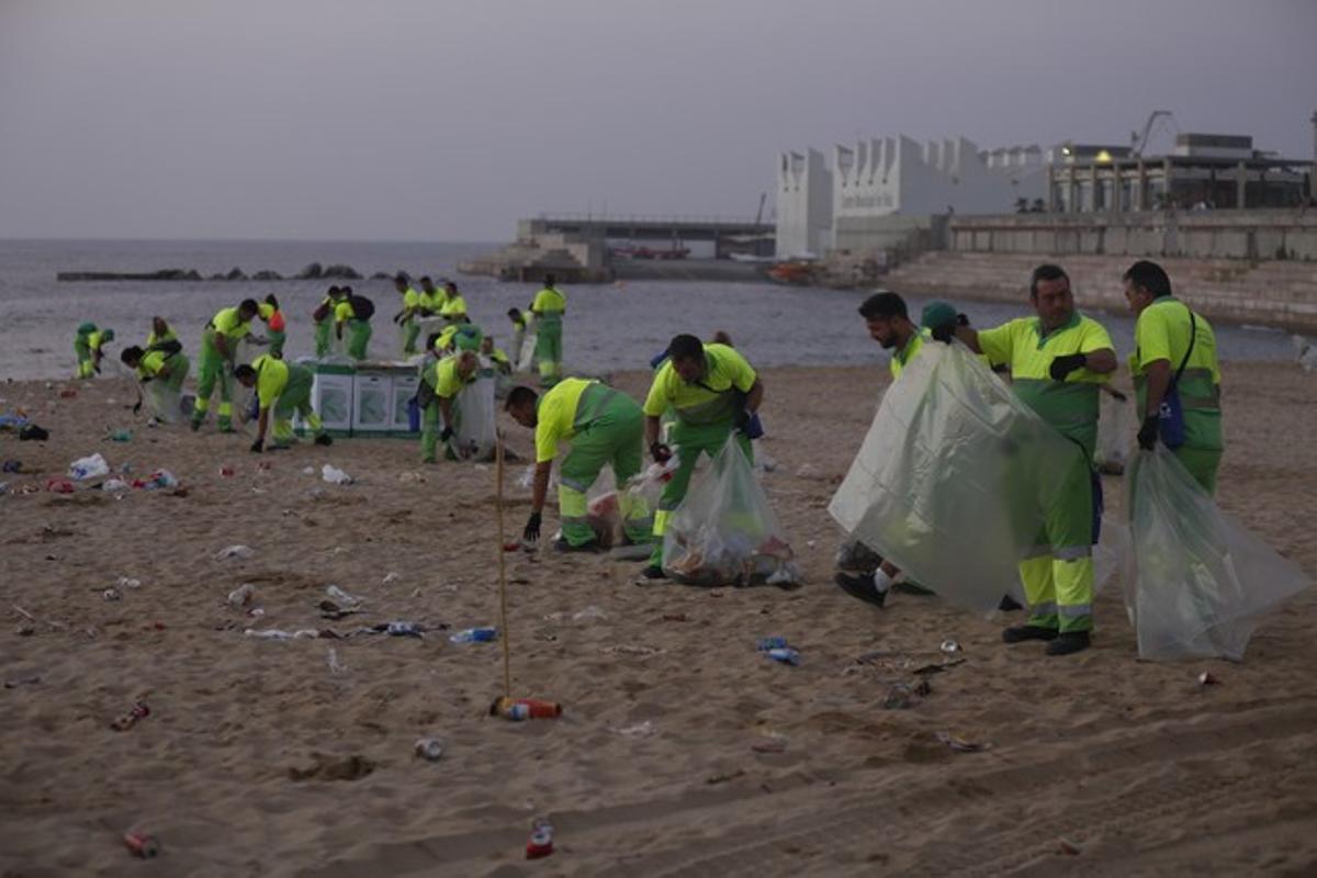 Operarios de limpieza del Ayuntamiento de Barcelona trabajan en la playa del Bogatell tras la verbena de Sant Joan.