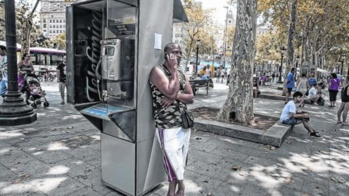 Un hombre habla por el teléfono móvil apoyado en una de las cabinas de la plaza de Catalunya, hace unos días.