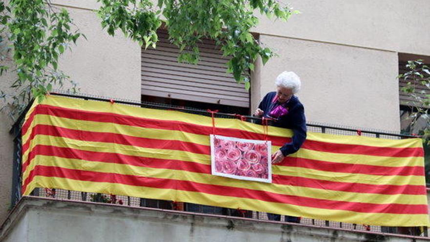 Una dona penja la foto d&#039;unes roses al seu balcó, sobre una senyera, a Barcelona