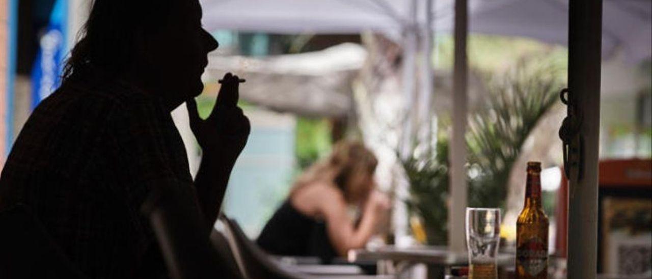 Un hombre fuma en una terraza.