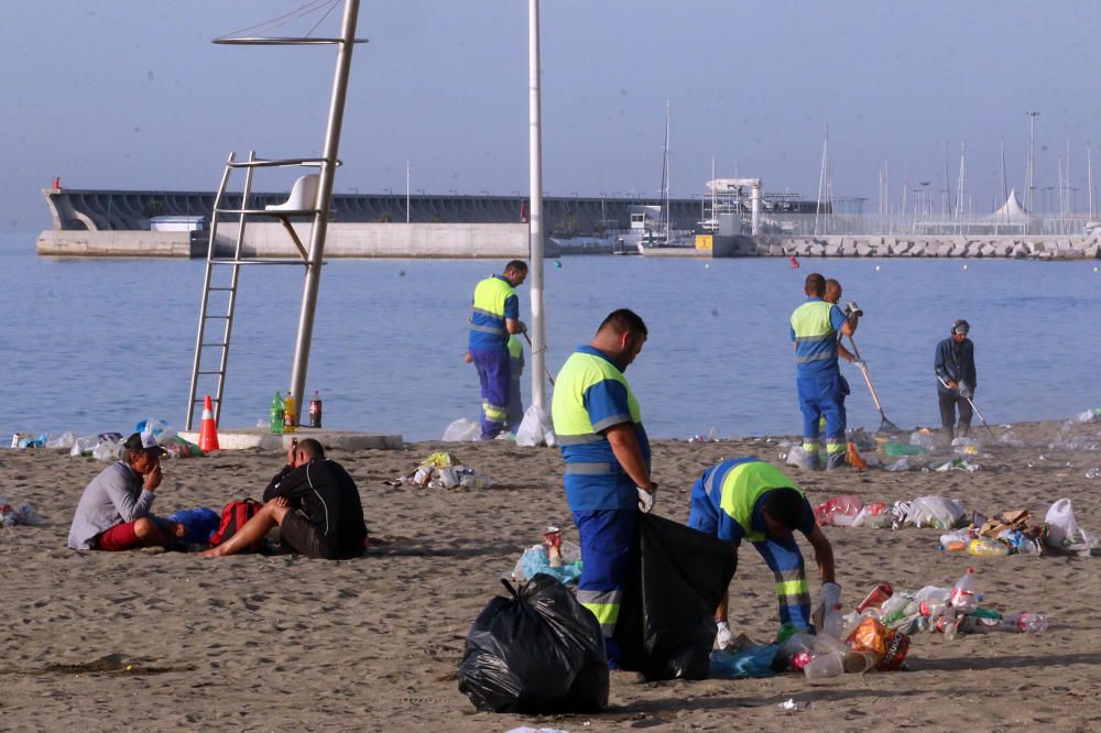 Los operarios de los servicios de limpieza trabajan para dejar la playa en óptimas condiciones tras una larga noche de fiesta en la arena