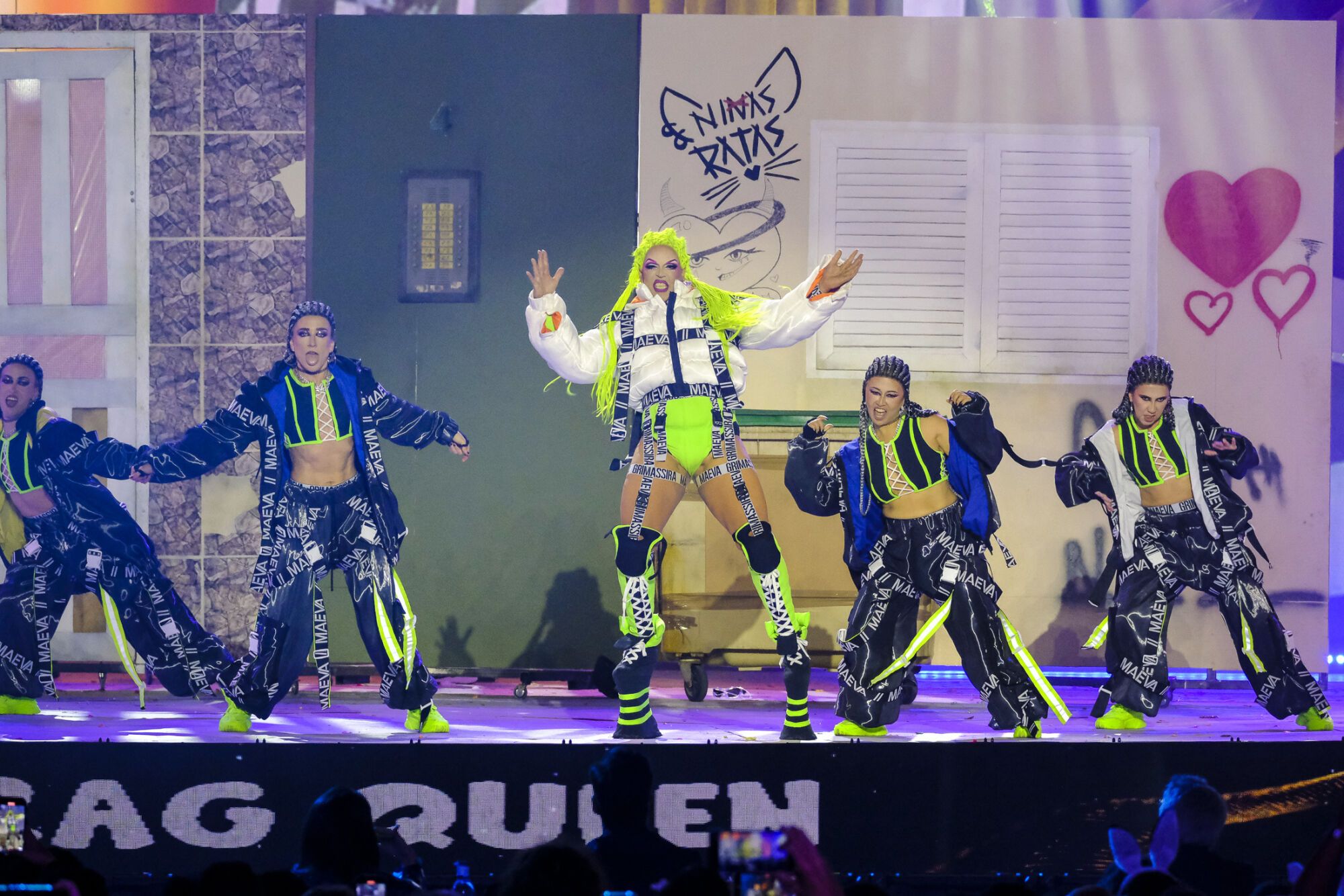 11. Drag Grimassira Maeva (Rayco Santana Peña) Con el patrocinio de Gael Automoción y Darque Car y con un diseño de Yassira Jurado, Grimanessa Dúrcal y Dani Viera presenta el espectáculo Érase una vez, en un bloque señorial del lejano Polígono de Jinámar, vivía la princesa Grimassera Maeva. Sus hermanastras, envidiosas y perversas, temían que Maeva, vestida con andrajos, siguiera triunfando en los bailes del reino.