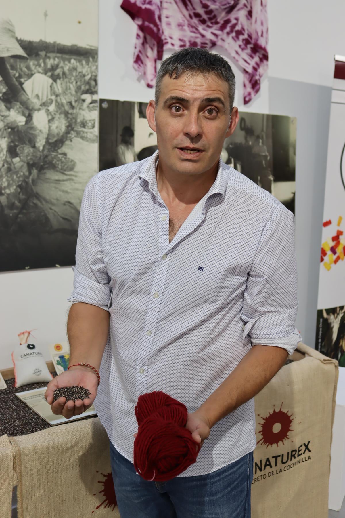 Lorenzo Pérez, con cochinilla seca en una mano y una madeja teñida en la otra.