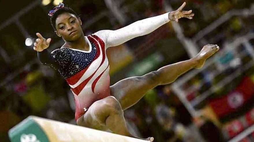 Biles, concentrada, durante un ejercicio en la barra de equilibrio.