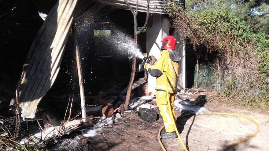 Un bombero apagando el fuego en la casa prefabricada