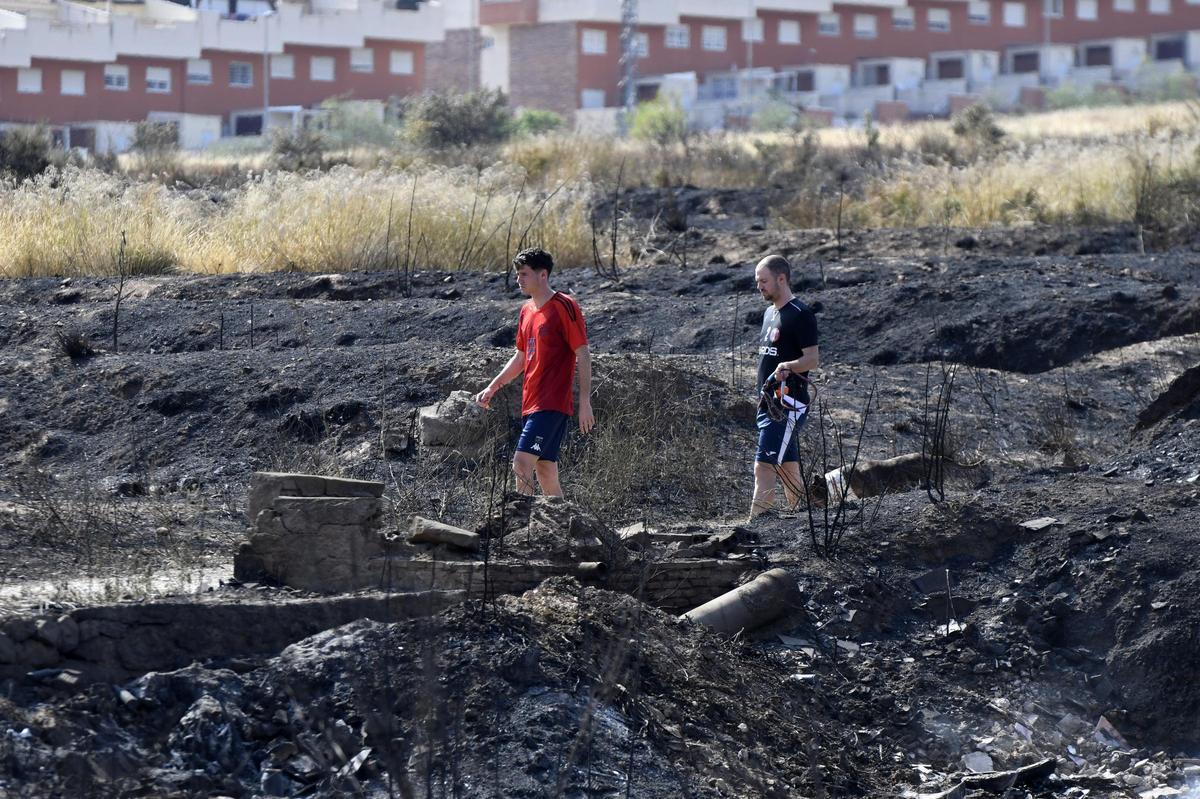 Dos vecinos pasean por una zona de la localidad devastada por las llamadas