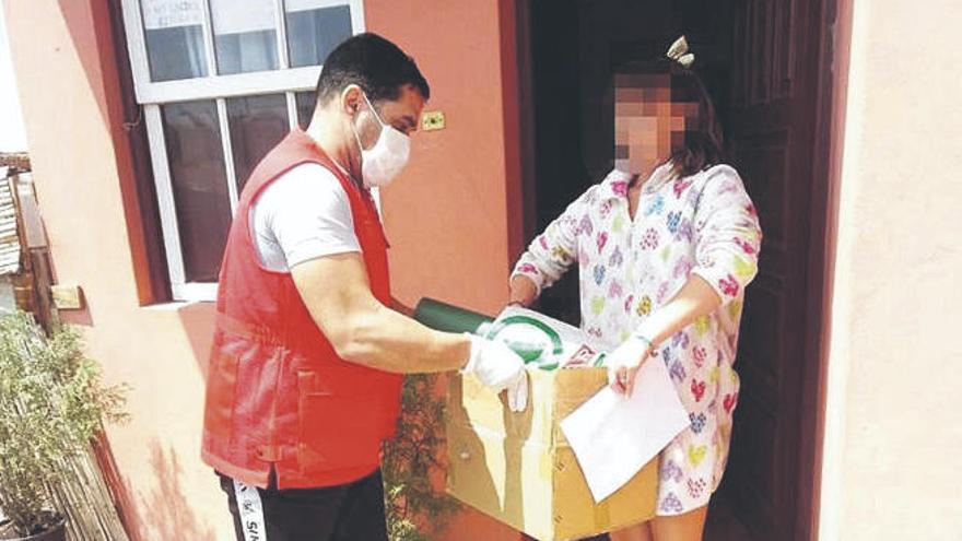 Un voluntario de Cruz Roja en La Palma entrega un lote de ayuda a una vecina de la Isla Bonita.