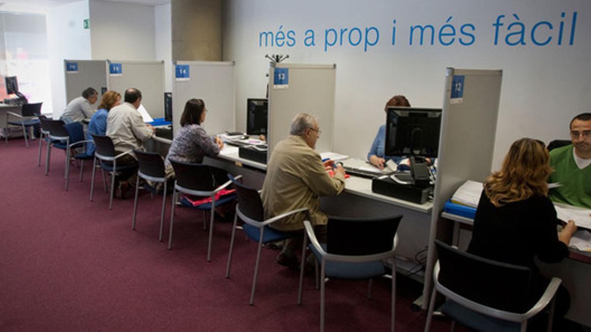 Varias personas tramitan su declaración del IRPF en una delegación de Hacienda en Barcelona, durante una anterior campaña de la renta. DANNY CAMINAL