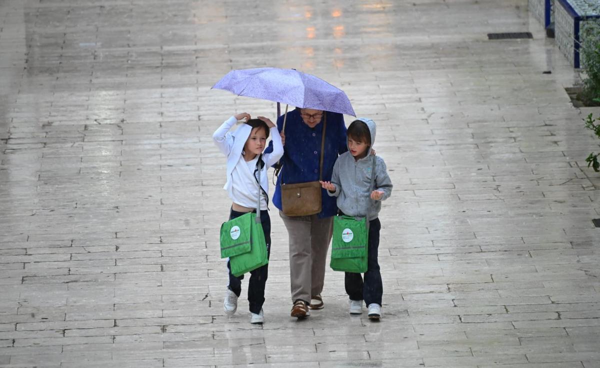 Varias personas se protegen de la lluvia con un paraguas este jueves en Elche