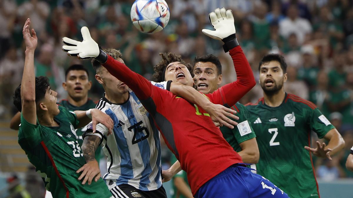 El portero de la selección de México, Guillermo Ochoa, agarrado por Lisandro Martínez de Argentina en un partido del Mundial