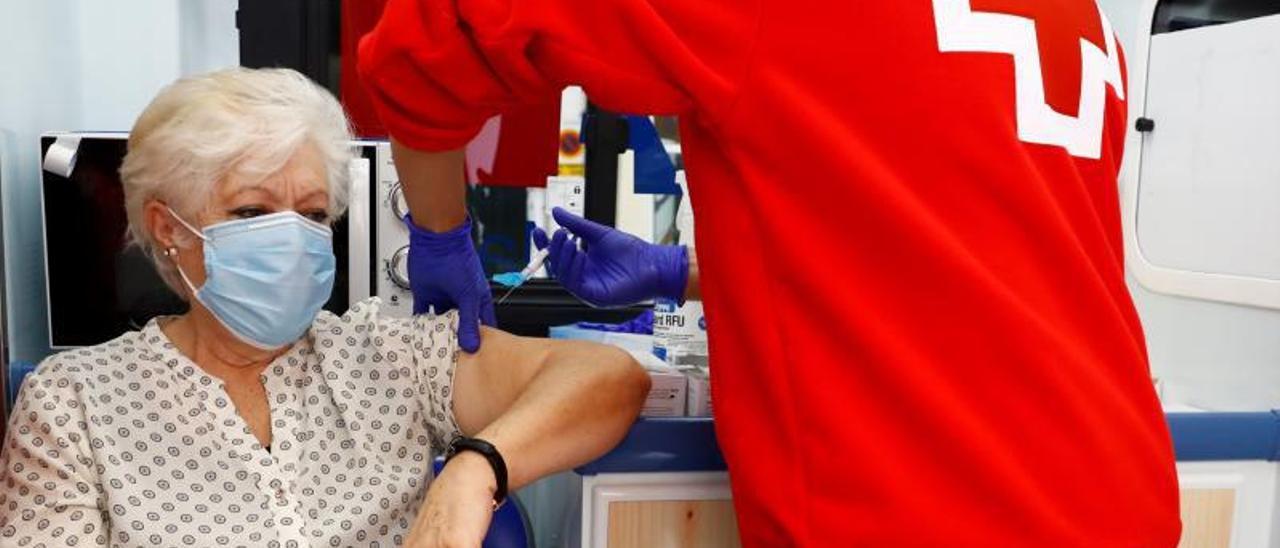 Un miembro de la Cruz Roja vacuna de la gripe a una mujer.