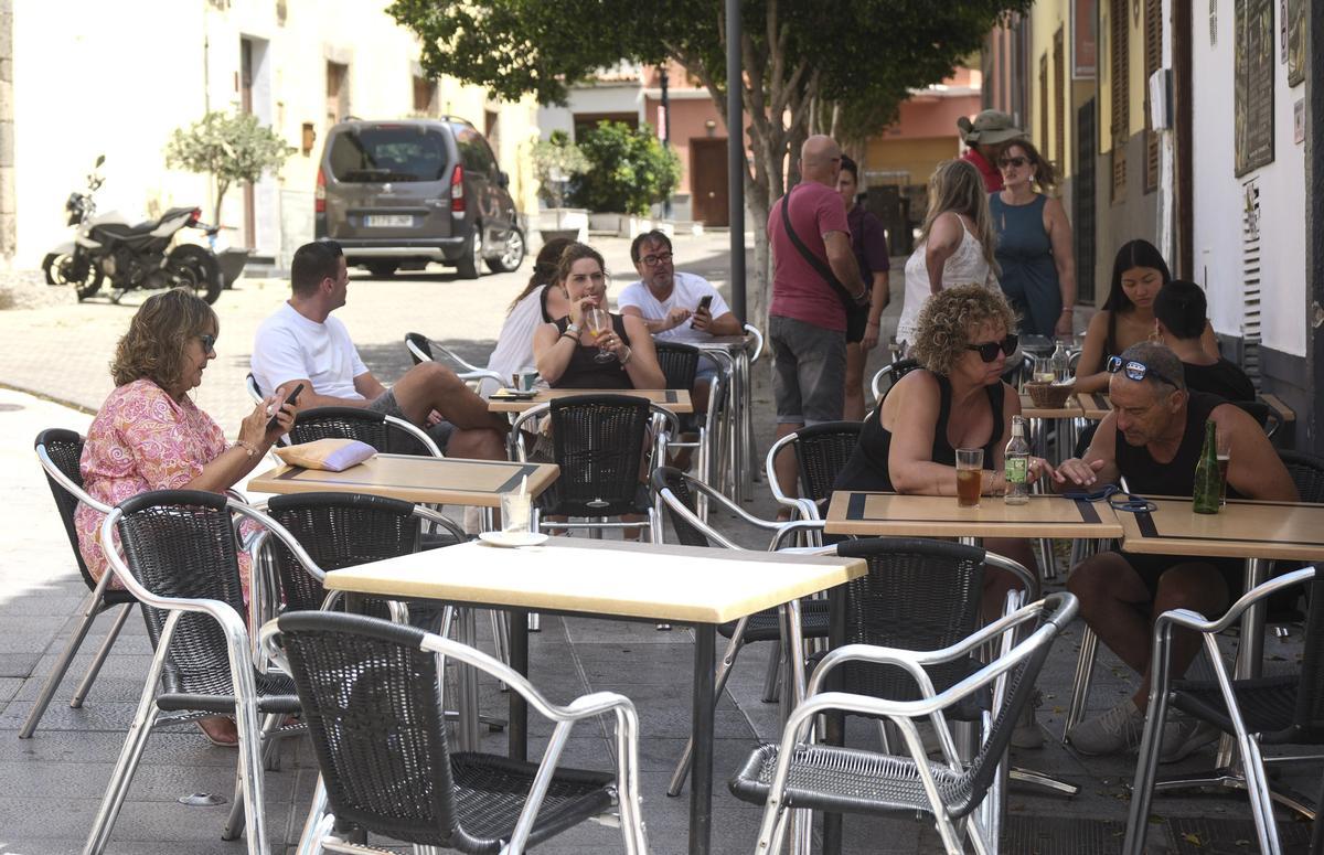 Turistas a la sombra se refrescan en una cafetería del centro de Agüimes.